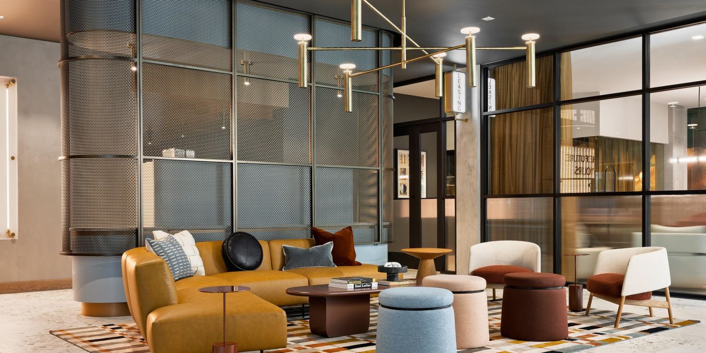 Ever West Lafayette modern lounge with colorful chairs, round tables, and geometric rug under a gold chandelier in a stylish room.