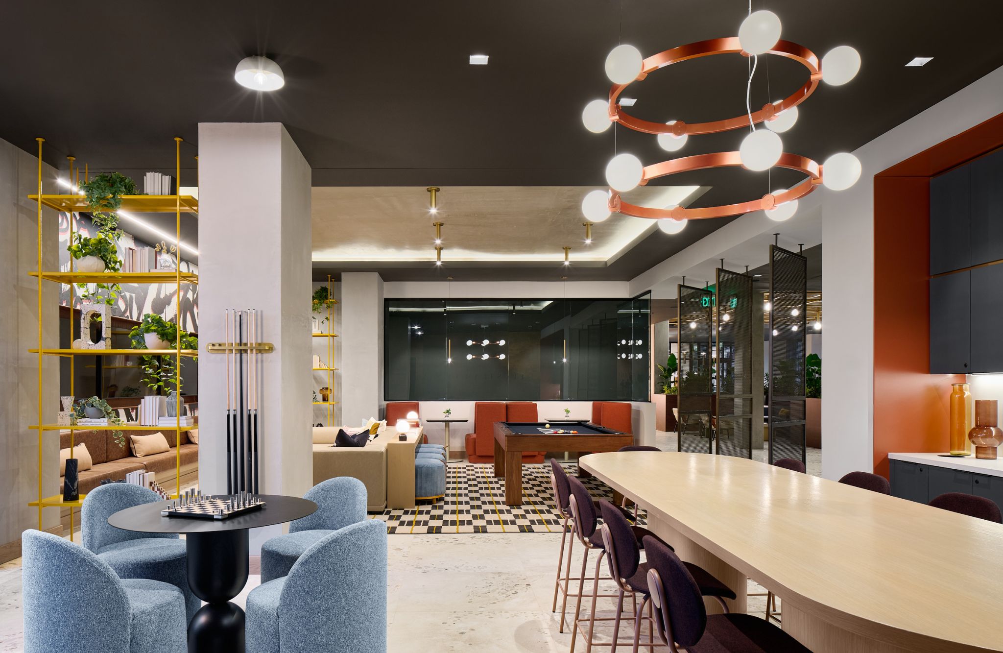 Salón moderno con cómodos asientos, mesa de billar, zona de comedor y lámparas contemporáneas.