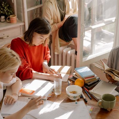 College girls doing homework together near open sunny window
