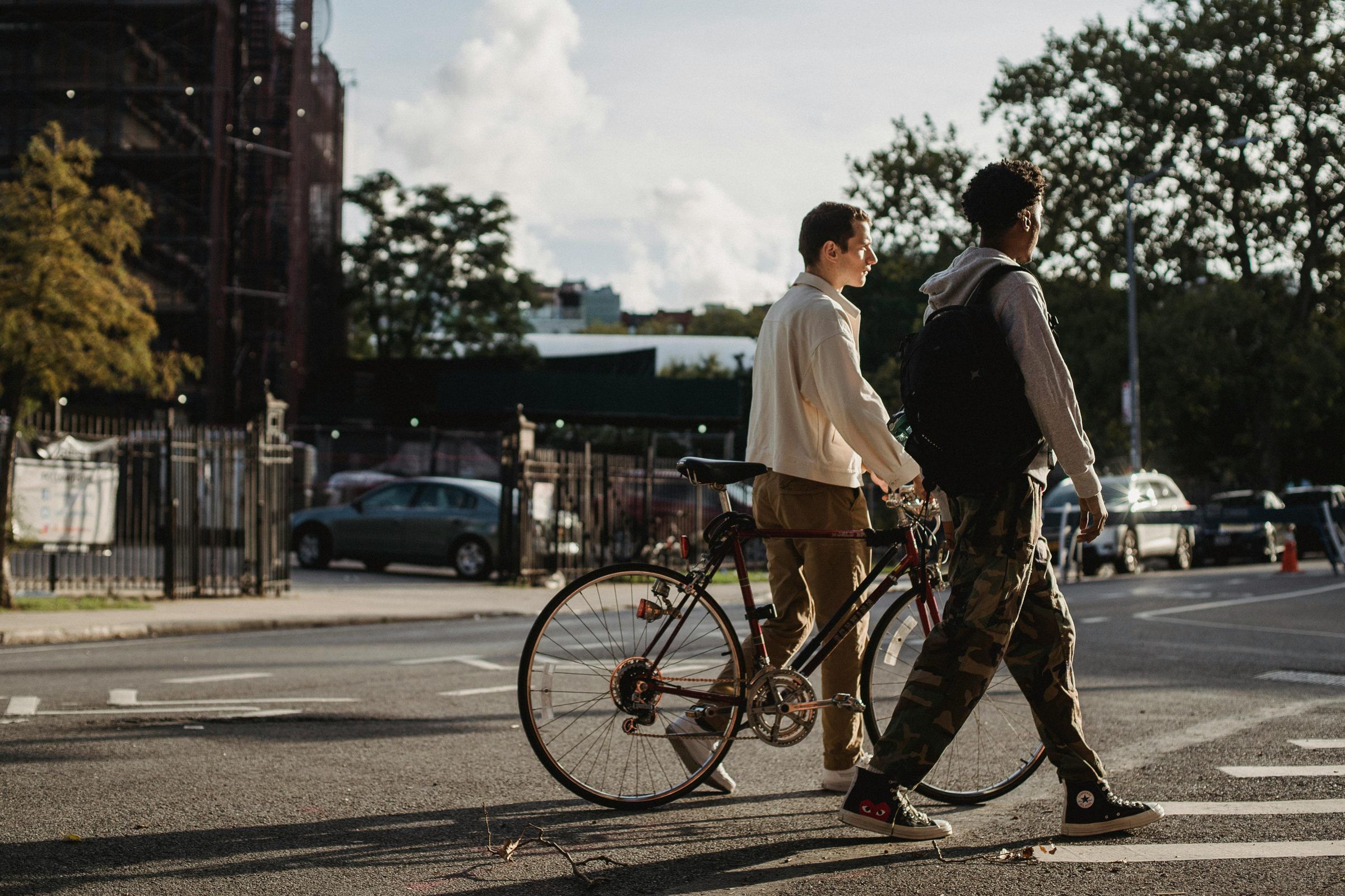 Two young men walking their bicycles down a city street