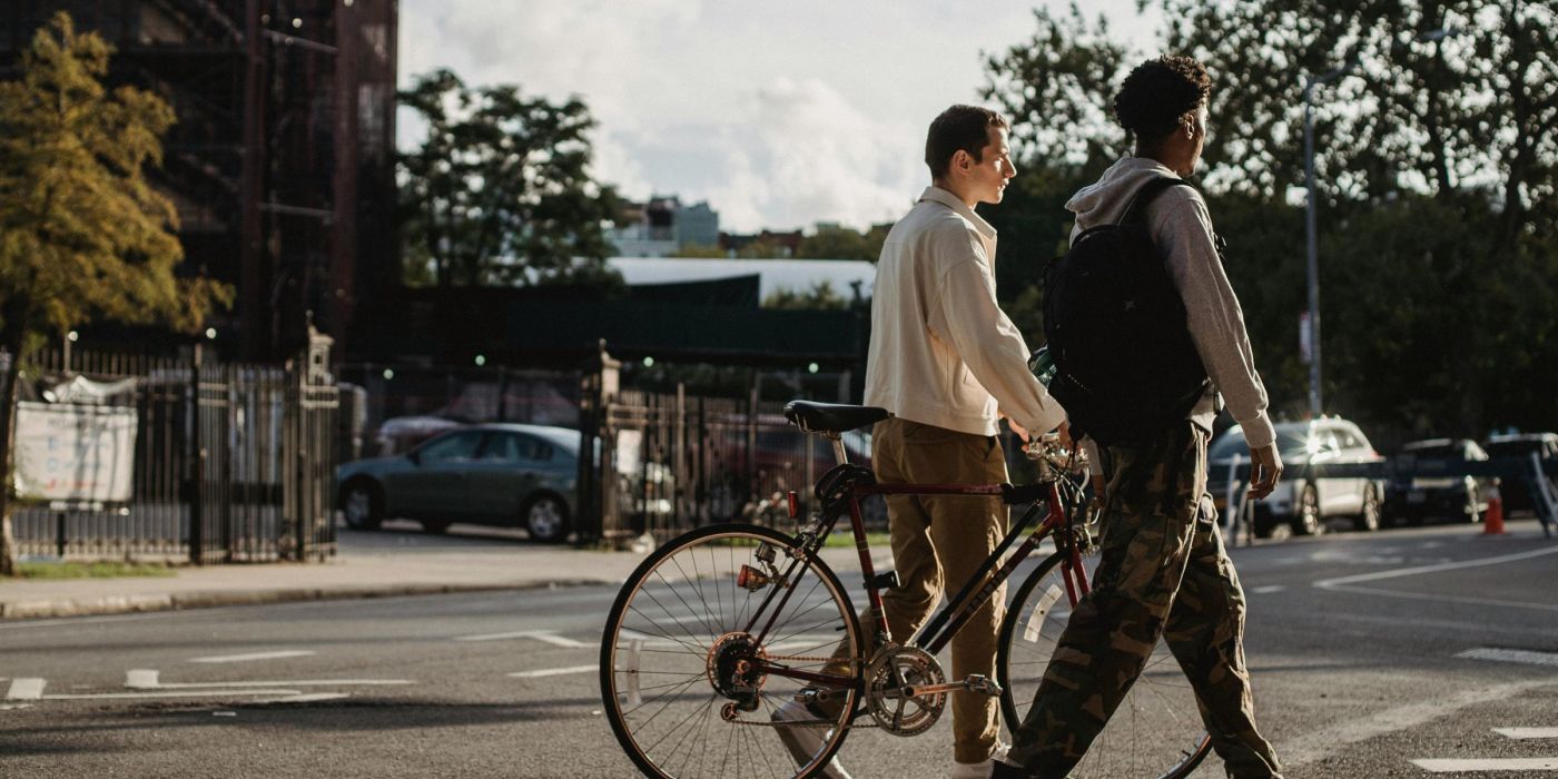 Two young men walking their bicycles down a city street