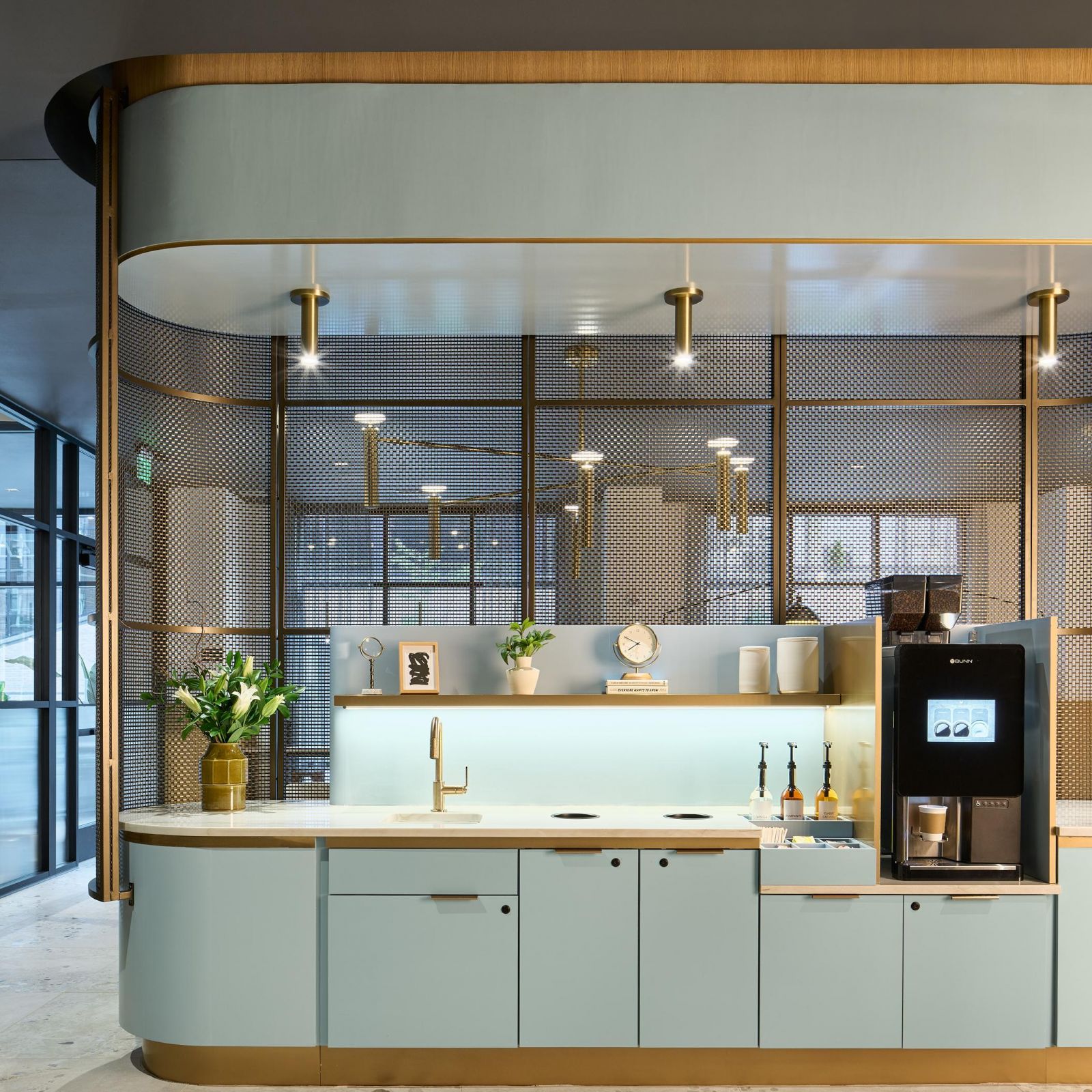 Ever West Lafayette modern coffee station with light blue cabinets, coffee machine, and decorative items on shelves, in a stylish office.