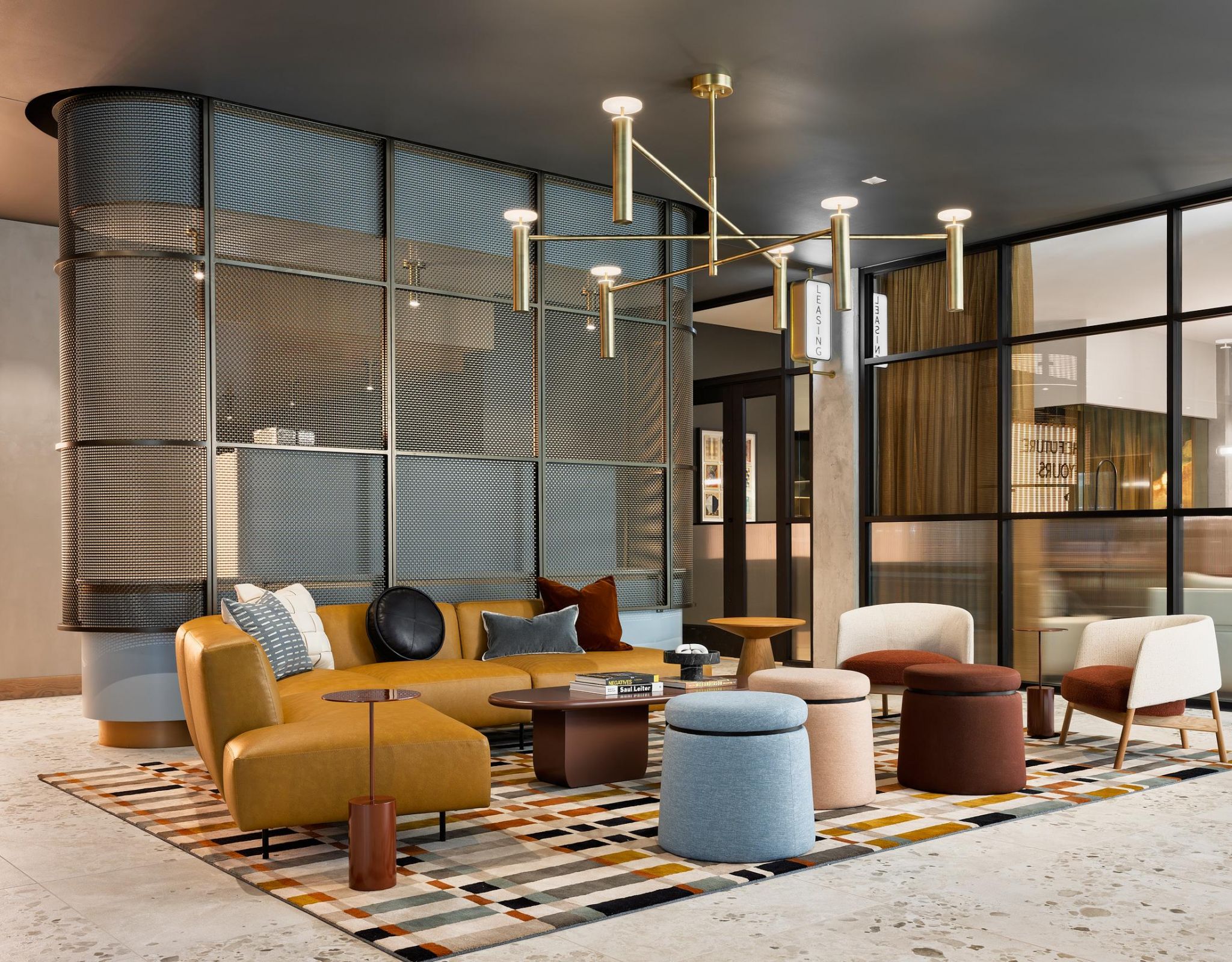 Ever West Lafayette modern lounge with colorful chairs, round tables, and geometric rug under a gold chandelier in a stylish room.