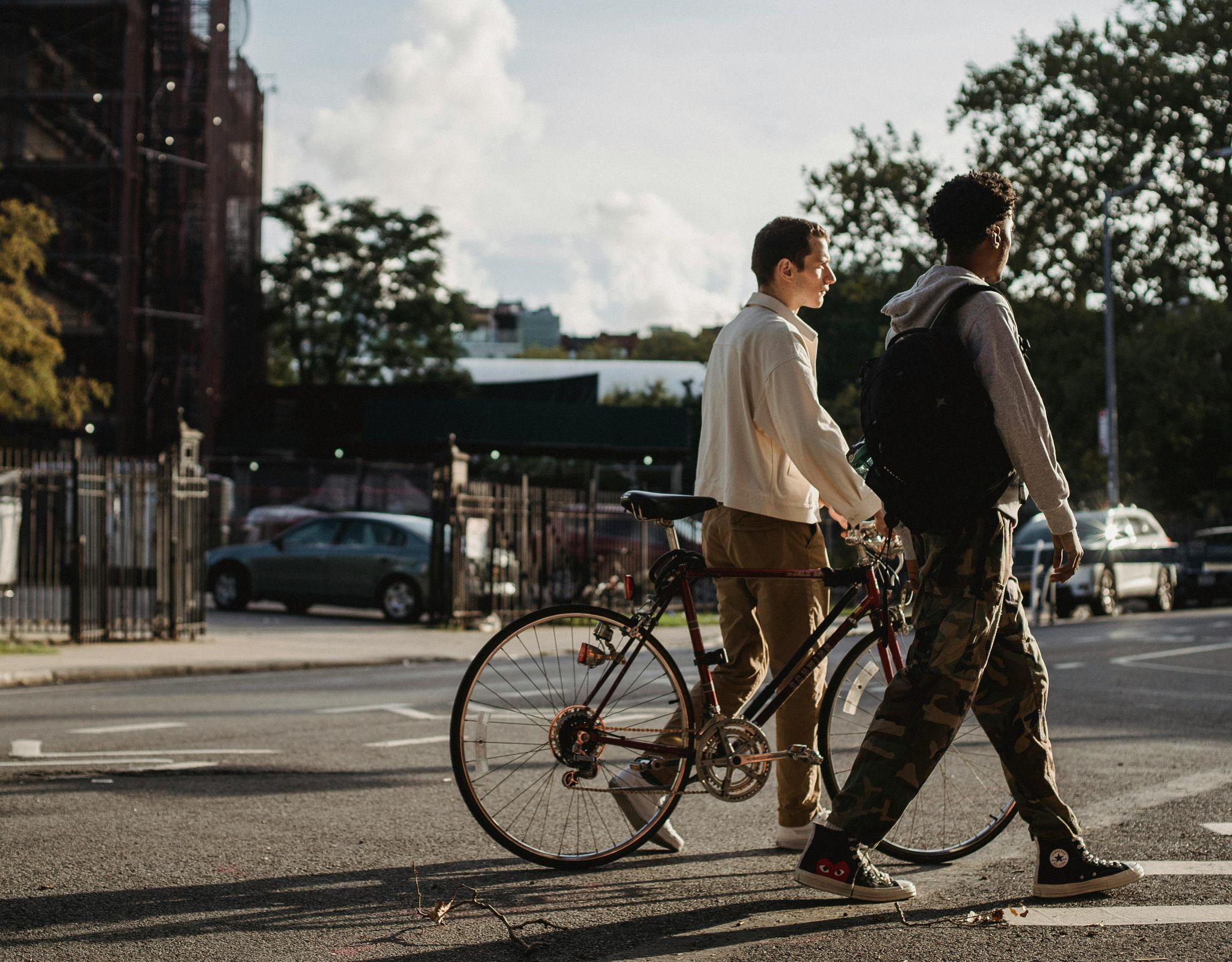 Two young men walking their bicycles down a city street