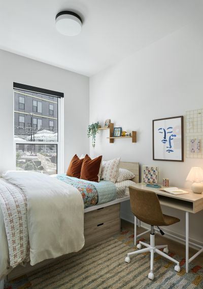 Ever West Lafayette cozy, modern bedroom with a bed, desk, and window letting in natural light.