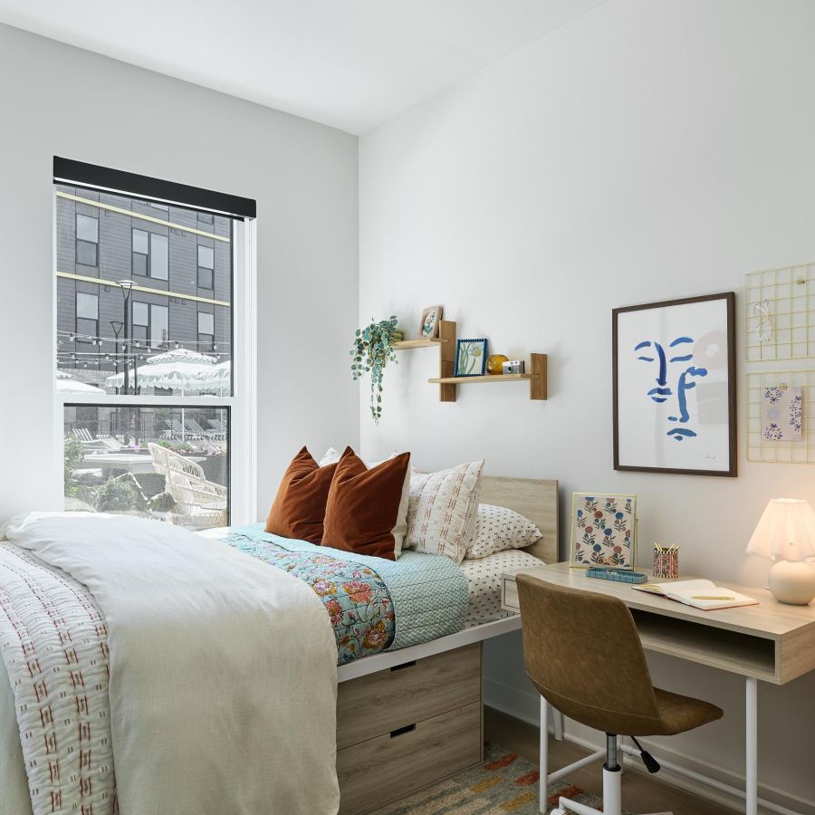 Habitación acogedora y moderna en West Lafayette con cama, escritorio y ventana que deja entrar la luz natural.