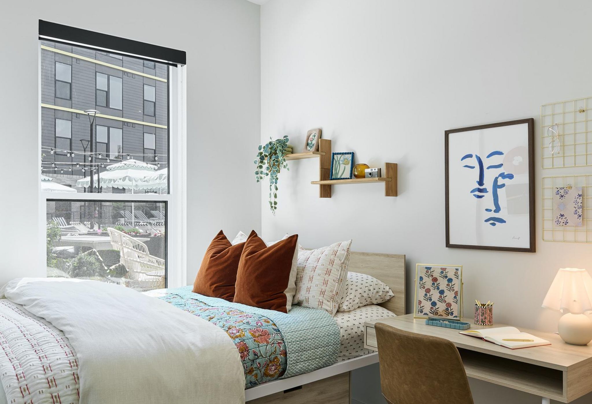 Ever West Lafayette cozy, modern bedroom with a bed, desk, and window letting in natural light.