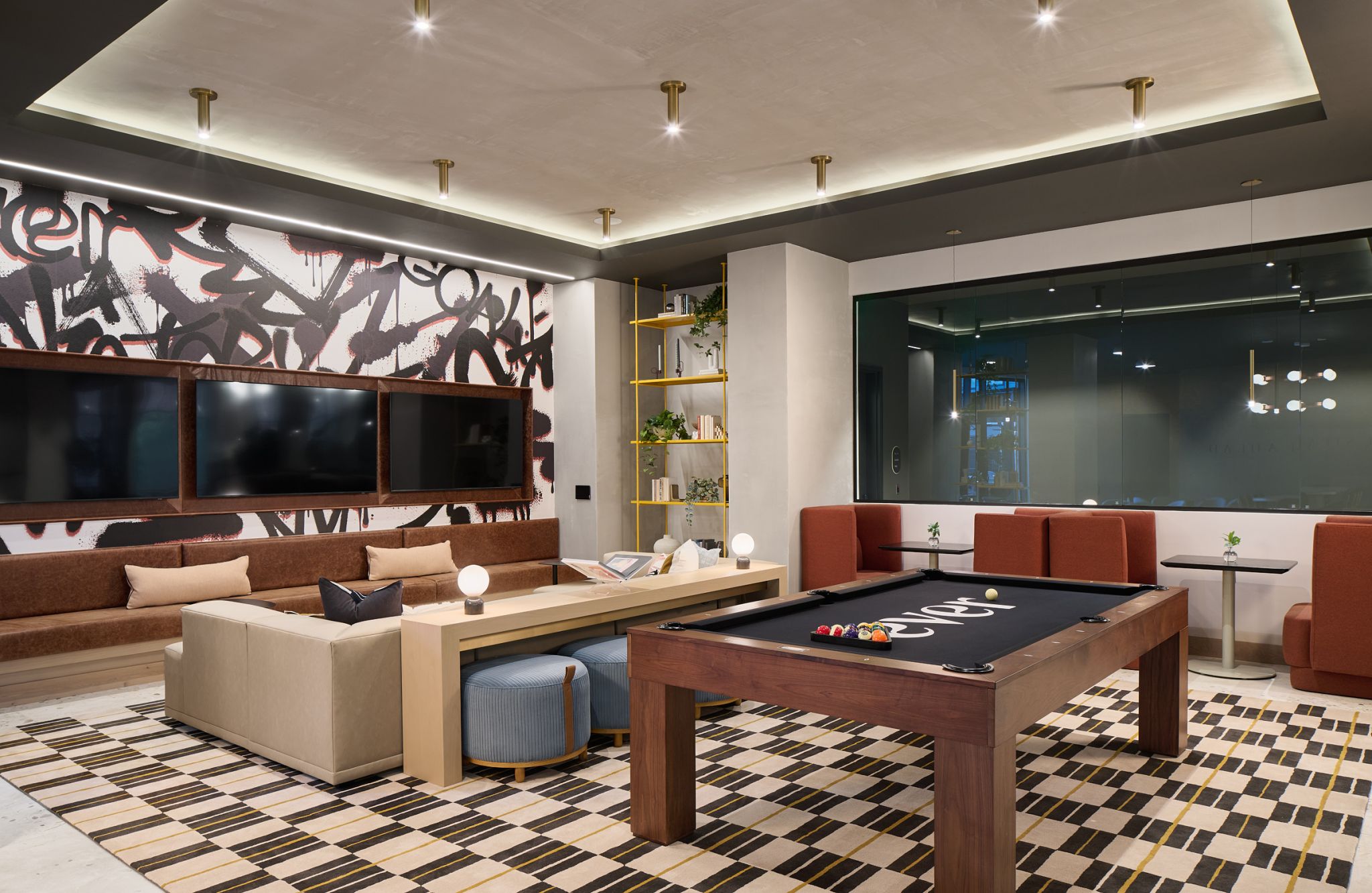 Modern lounge with pool table, TV screens, couches, wall art, and contemporary lighting.