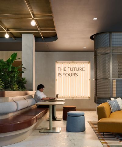 Ever West Lafayette person working on a laptop in a modern lounge with a sign reading “THE FUTURE IS YOURS” on the wall.